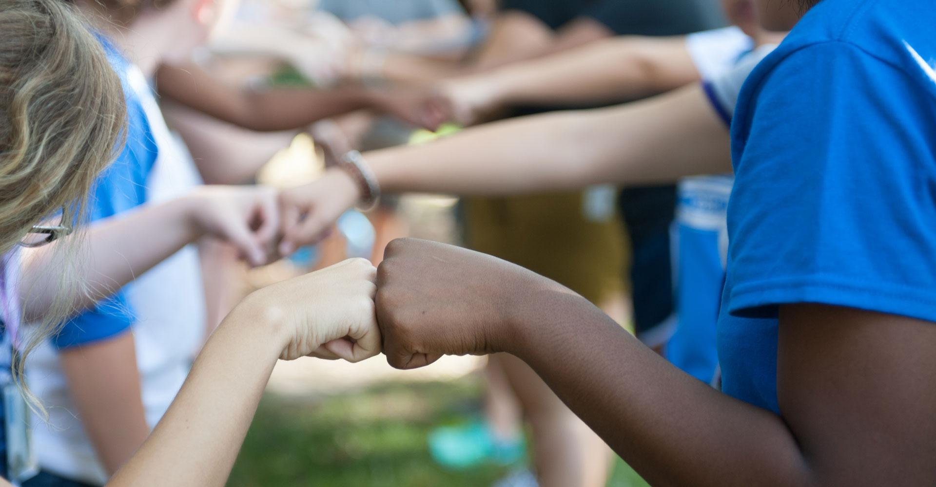 Agnes Scott Summit students give each other fist bumps.